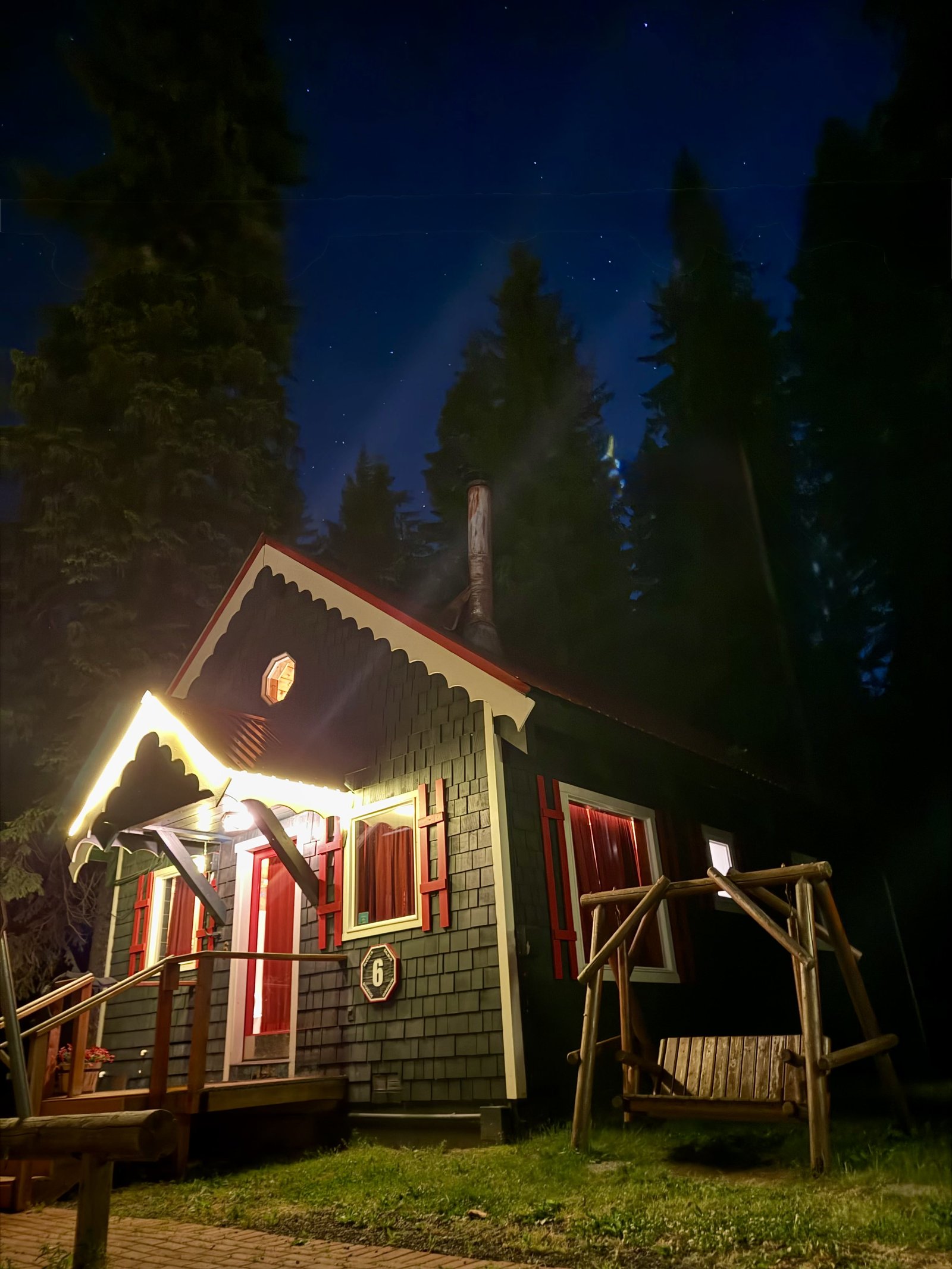 A bungalow lit up at night under a starry sky, string lights along the gable